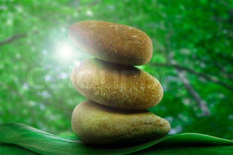 Stacked stones on base of green leafs. Green natural background, stock photo