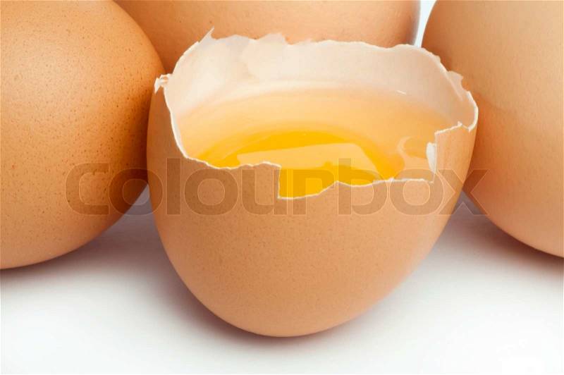 Tree whole eggs and another broken in half raw egg and yolk inside. Placed on white background, stock photo