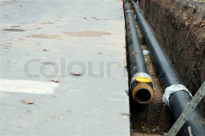 Installing pipes for hot water and steam heating. City heat pipeline, stock photo