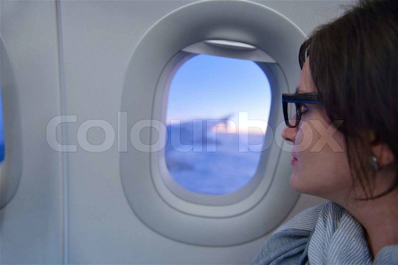 Happy young tourist woman is sitting in the airplane looking window and travel to summer vacation, stock photo