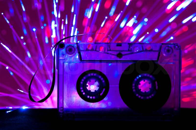 Transparent Cassette tape and blue pink color disco light background, stock photo