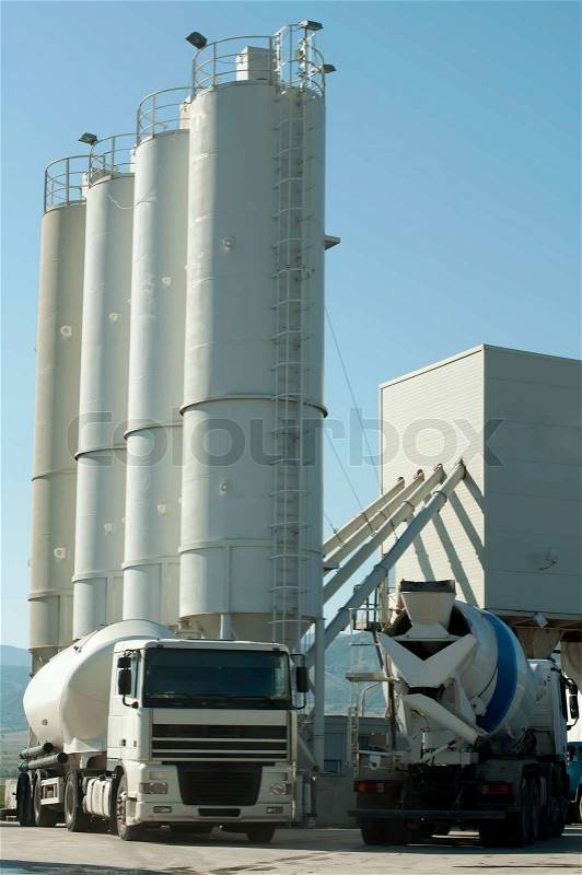 Cement factory and two white trucks loading cement, stock photo