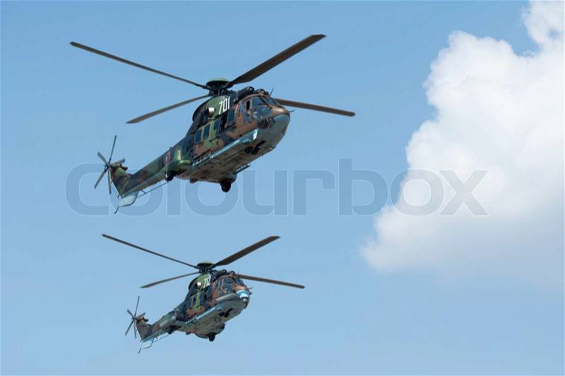 Two green military helicopters on blue sky background, stock photo