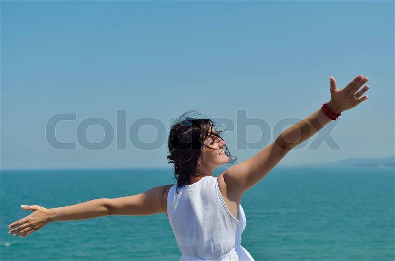 Happy young woman with spreading arms, blue sky with clouds in background - copyspace, stock photo