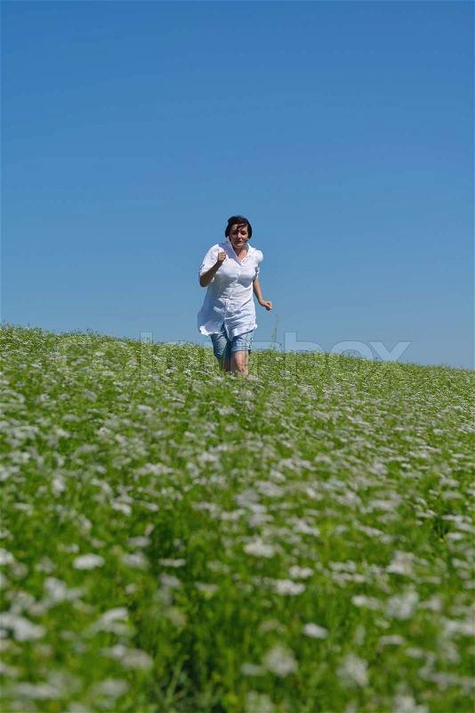 Young happy woman in green field with blue sky in background, stock photo