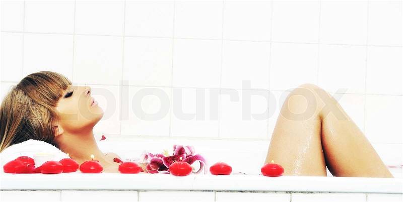 Woman beauty spa and wellness treathment with red flower petals in bath, stock photo
