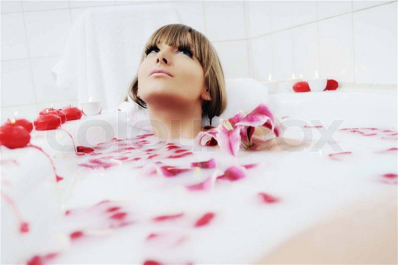 Woman beauty spa and wellness treathment with red flower petals in bath, stock photo