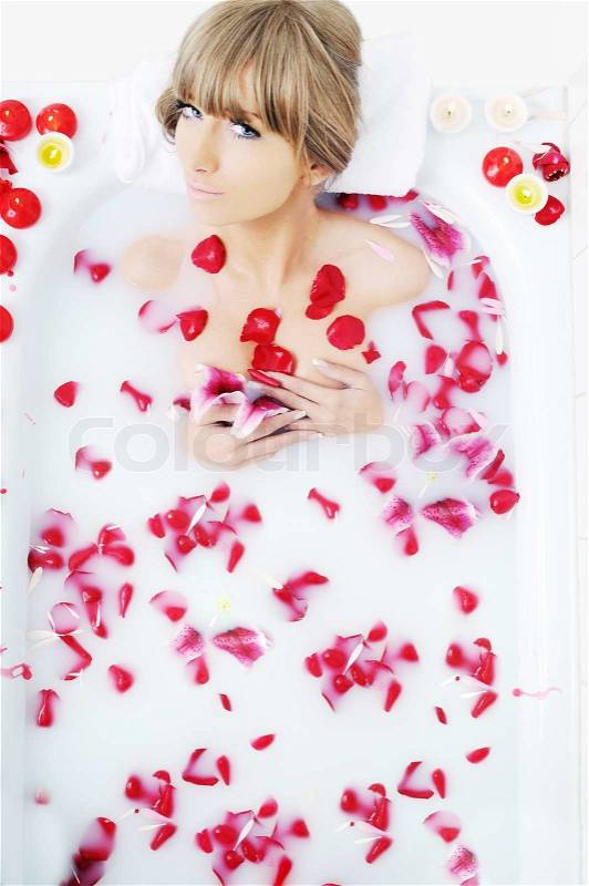 Woman beauty spa and wellness treathment with red flower petals in bath with milk , stock photo