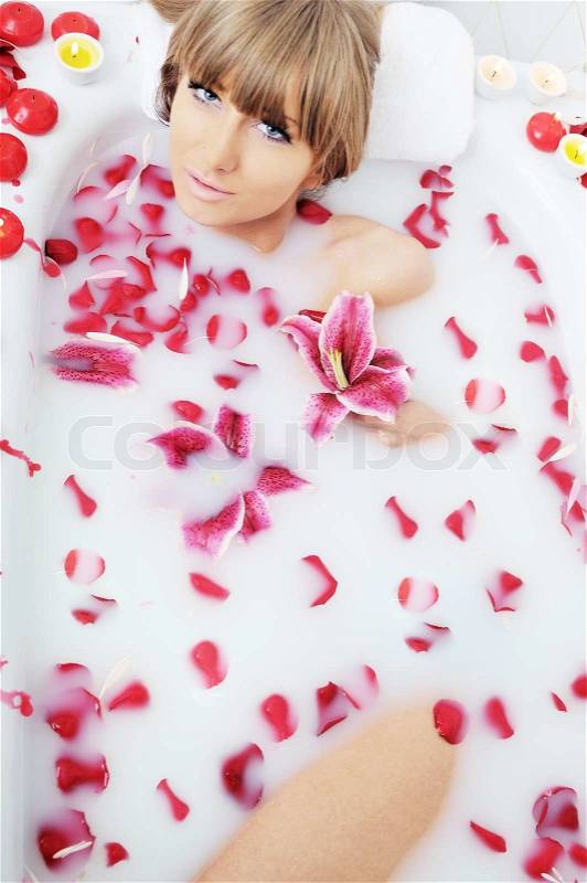Woman beauty spa and wellness treathment with red flower petals in bath with milk , stock photo