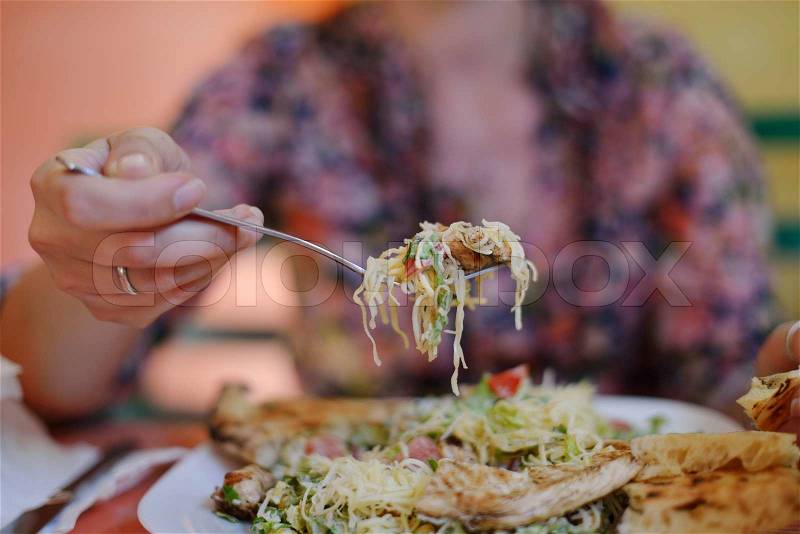 Woman eat tasty chicken salad with fresh vegetables and cheese in retro kitchen, stock photo