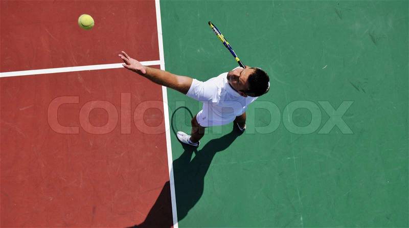 Young man play tennis outdoor on orange tennis court at early morning, stock photo