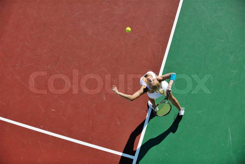 Young fit woman play tennis outdoor on orange tennis field at early morning , stock photo