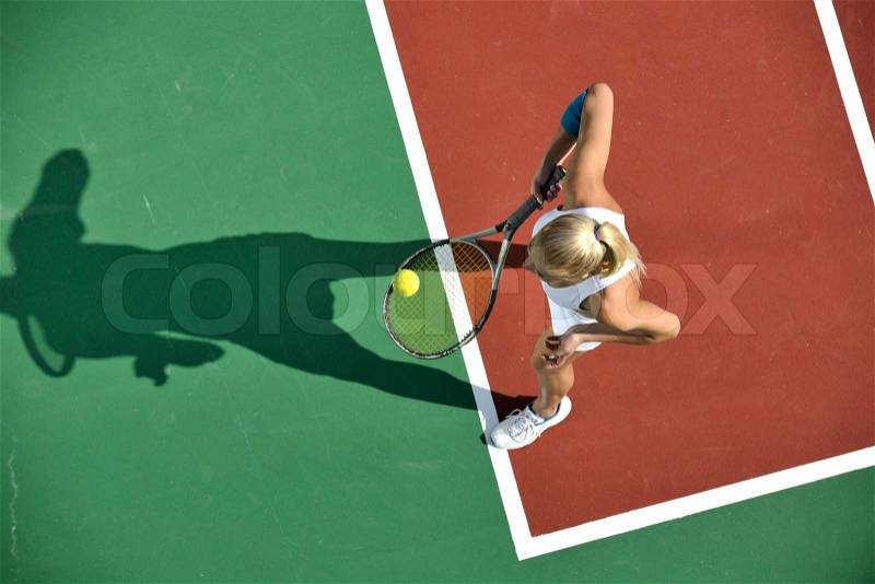 Young fit woman play tennis outdoor on orange tennis field at early morning, stock photo