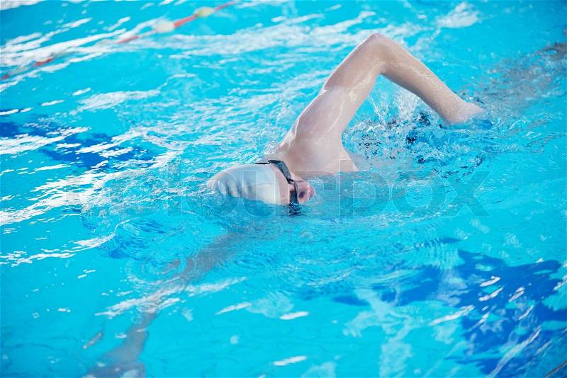 Happy muscular swimmer wearing glasses and cap at swimming pool and represent health and fit concept, stock photo