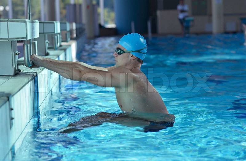 Happy muscular swimmer wearing glasses and cap at swimming pool and represent health and fit concept, stock photo