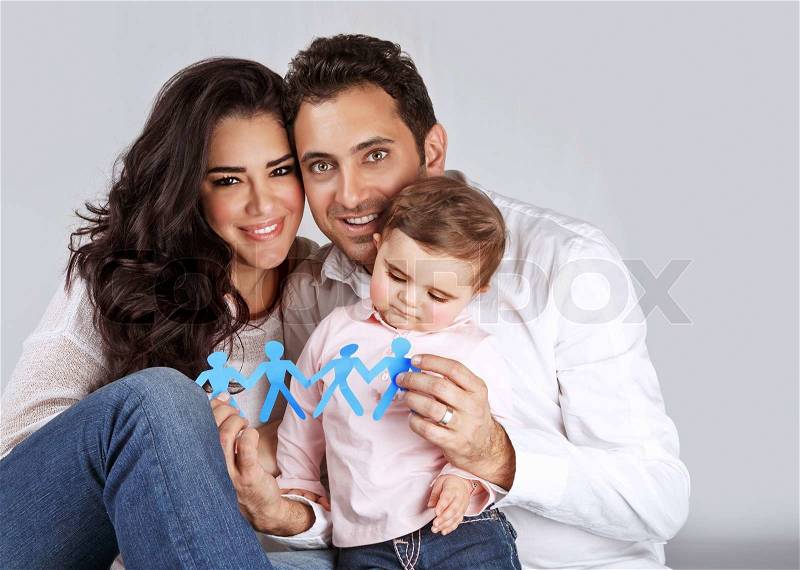 Portrait of cute arabic family sitting in the studio and holding in hands blue men-shape bonding paper, people unity concept, stock photo