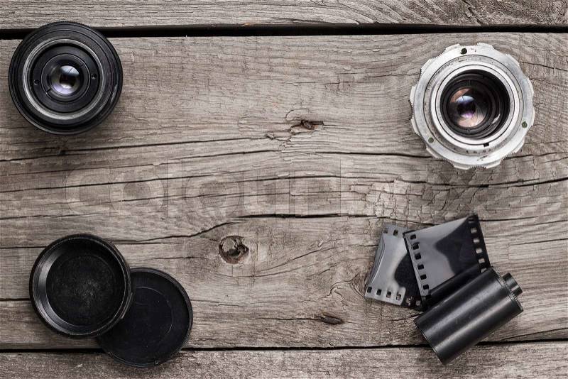 Retro camera lenses and negative film on wooden table, stock photo