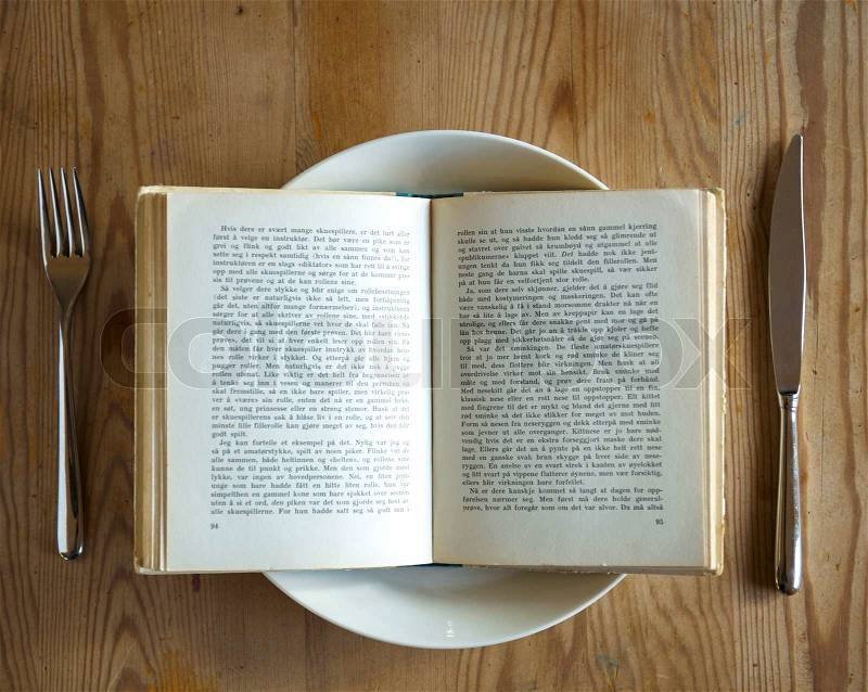 A plate with a book on it with cutlery, ready to be served, stock photo
