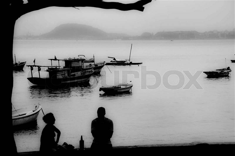 Silhouettes of people and boats at late afternoon in Rio de Janeiro, Brazil, stock photo