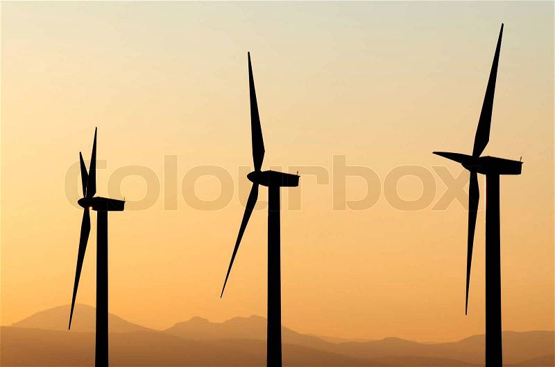 Aligned windmills for renowable electric production at sunset, stock photo