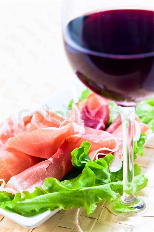 Glass with red wine and ham with salad , stock photo