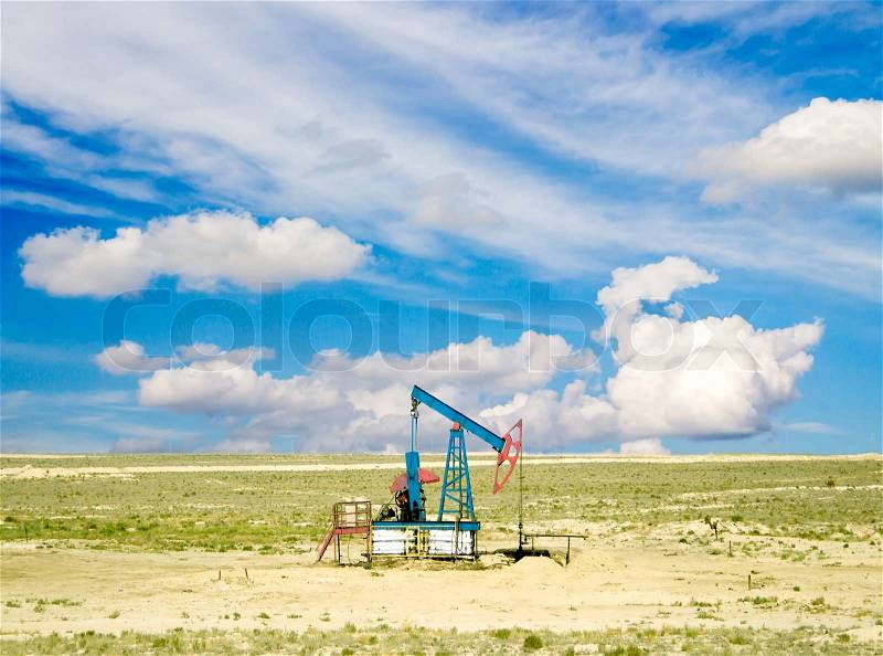 Pumping oil from an oil well on the background of sky with clouds, stock photo