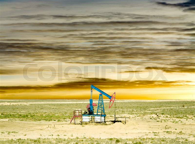 Pumping oil from an oil well on the background of sky with clouds, stock photo