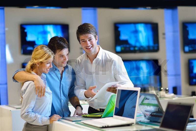 Young couple in consumer electronics store looking at latest laptop, television and photo camera, stock photo