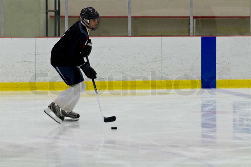 Hockey player stickhandles the puck, stock photo