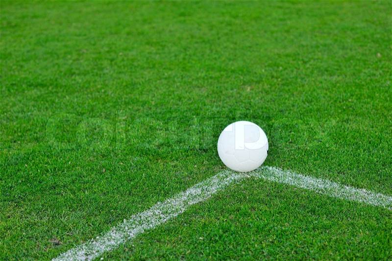 White Soccer ball on grass at goal and stadium in background, stock photo