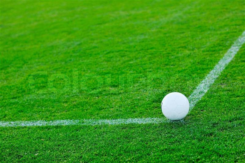 White Soccer ball on grass at goal and stadium in background, stock photo