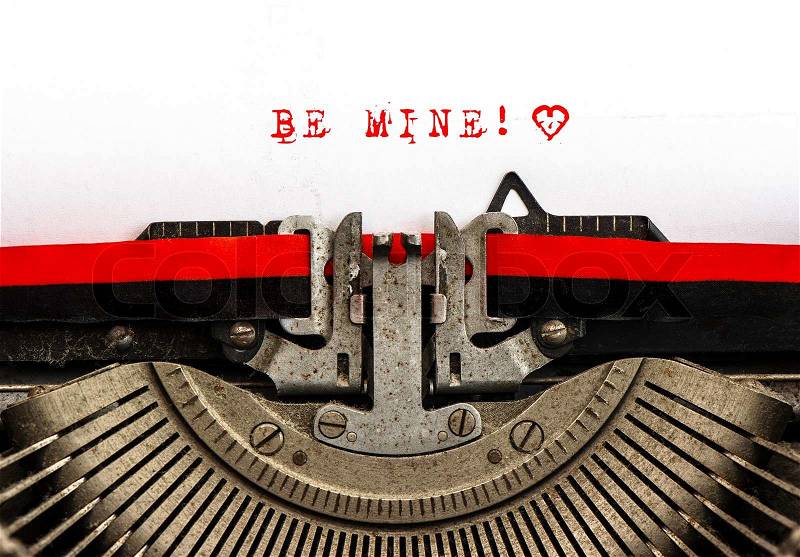 Old typewriter with sample text BE MINE! Red words on white paper, stock photo