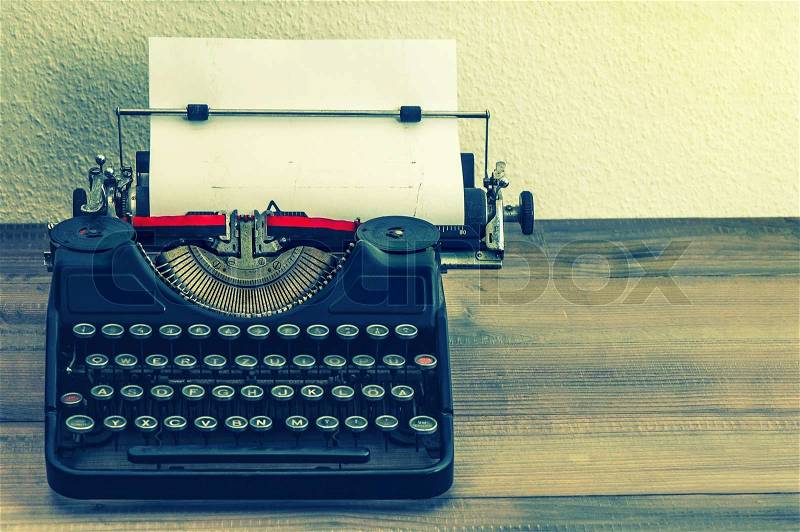Retro typewriter with white paper page on wooden table. vintage style toned picture, stock photo