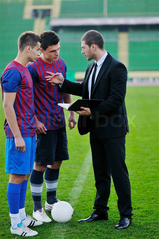Soccer sport manager in business suit coach and football player on stadium with green grass and white ball, stock photo