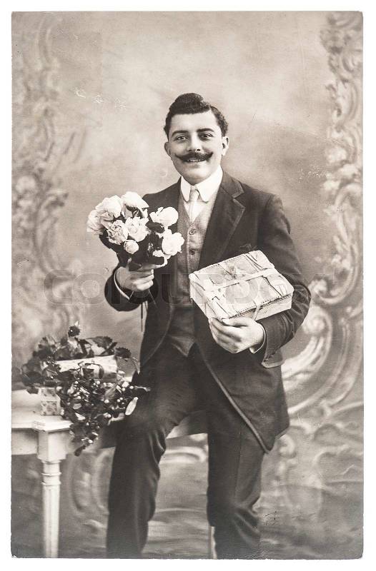 FRANCE, PARIS - CIRCA 1920: portrait of young man with rose flowers and gift. Typical for this period mans look. Illustrative Image, subject of human interest , stock photo