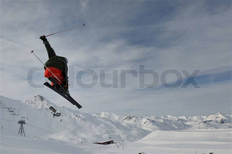 Extreme freestyle ski jump with young man at mountain in snow park at winter season, stock photo