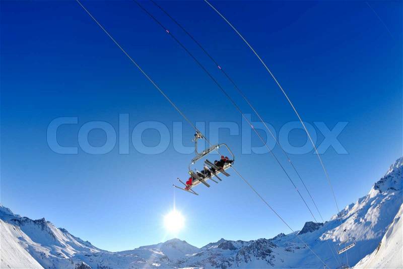 Ski lift - happy skiers use vertical transport on ski vacation at sunny winter snow day, stock photo