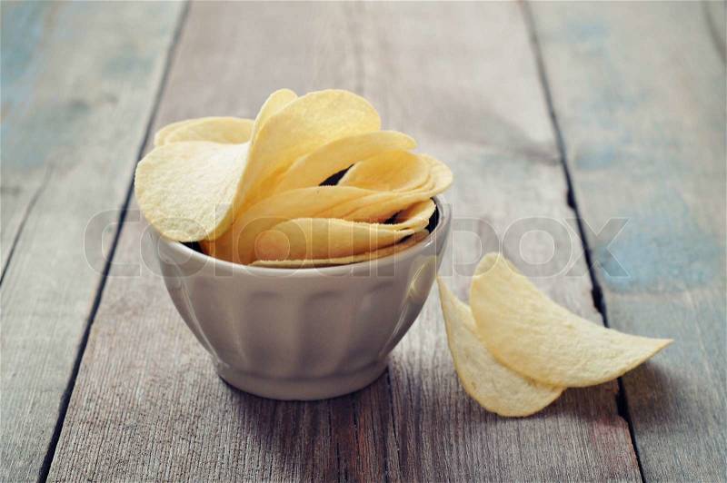 Potato chips in bowl on wooden backgrpond, stock photo