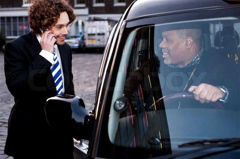 Taxi cab driver communicating with male passenger, stock photo