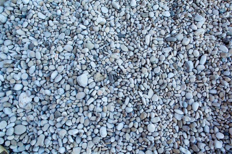 Naturally polished white rock pebbles background on beach, stock photo