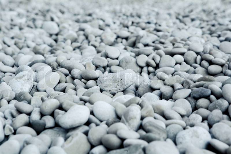 Naturally polished white rock pebbles background on beach, stock photo