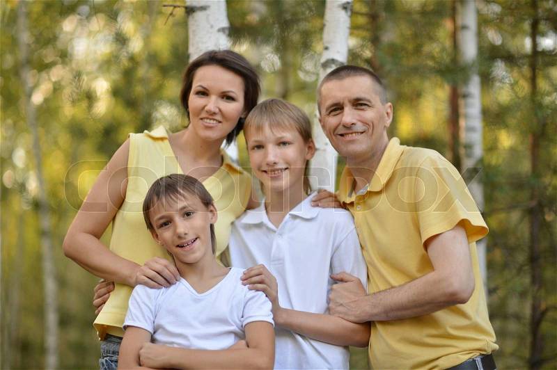 Family of four is having fun in a green summer park, stock photo