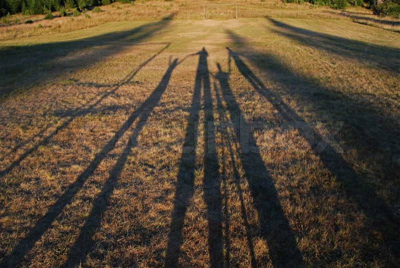 Family chain concpet with four shadows in field, stock photo