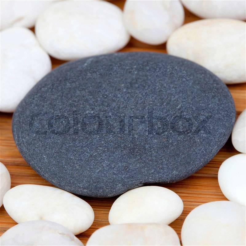 Large black stone surrounded by small white stones, stock photo