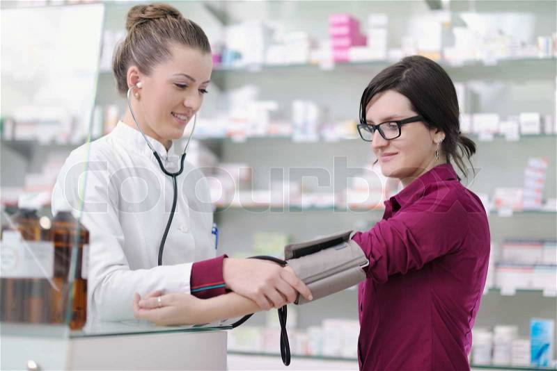 Doctor checking blood pressure and heart rate in a hospital or in pharmacy with young female patient, stock photo