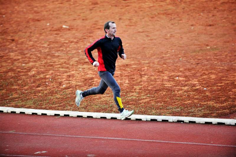 Adult man running on athletics track and representing healthy and recreation concept, stock photo
