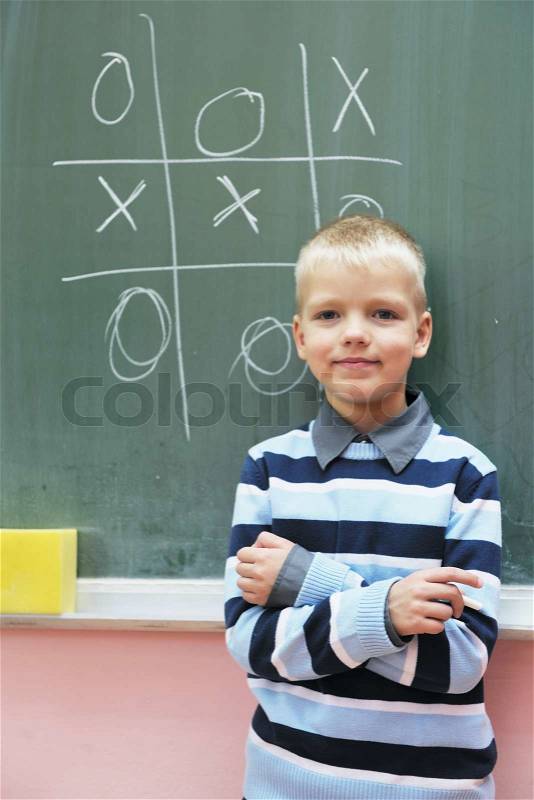 Happy young boy at first grade math classes solving problems and finding solutions, stock photo