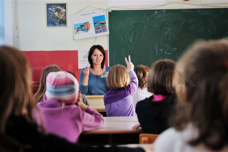 Happy young teacher woman at elementrary school teaching and giving leassons to group of young smart children, stock photo
