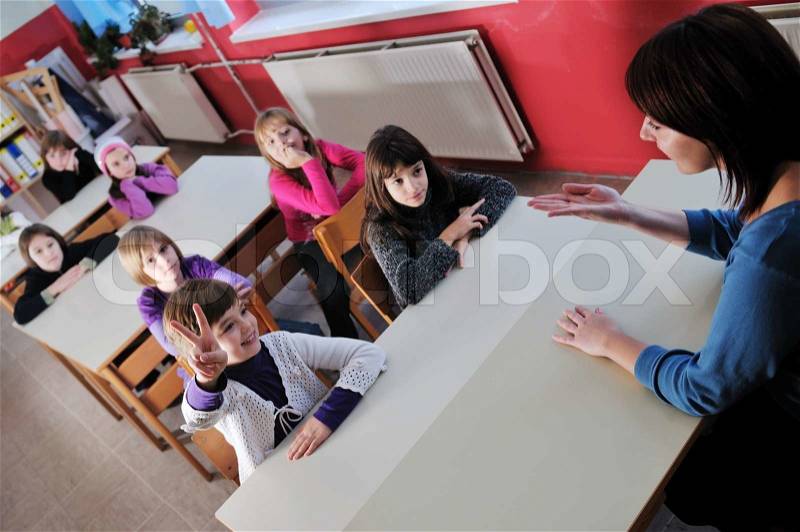 Happy young teacher woman at elementrary school teaching and giving leassons to group of young smart children, stock photo