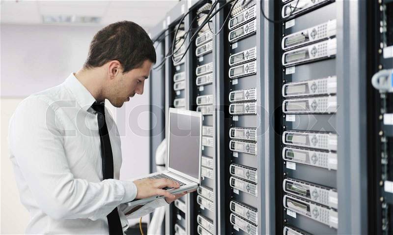 Young it engeneer business man with thin modern aluminium laptop in network server room, stock photo